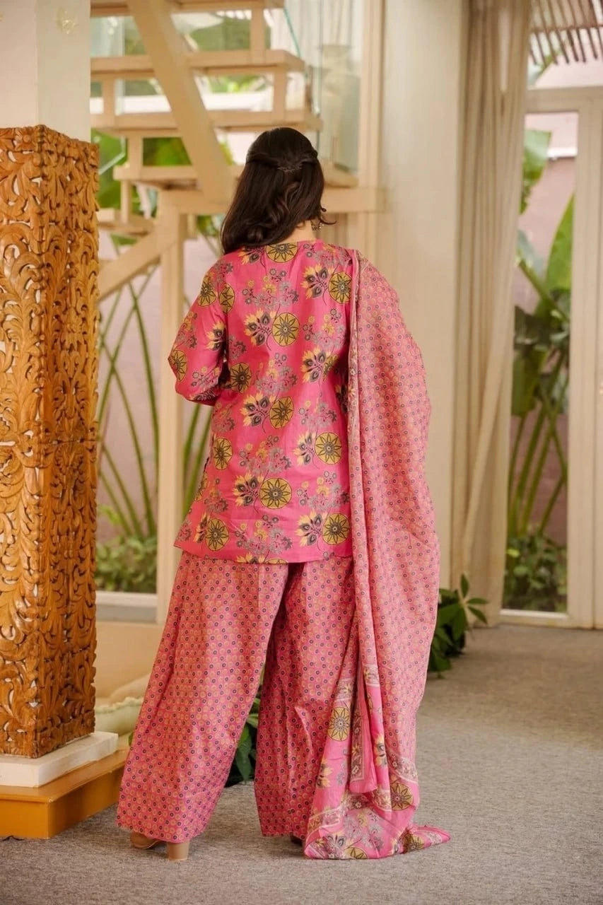 Person wearing a pink traditional outfit with floral patterns in an indoor setting.