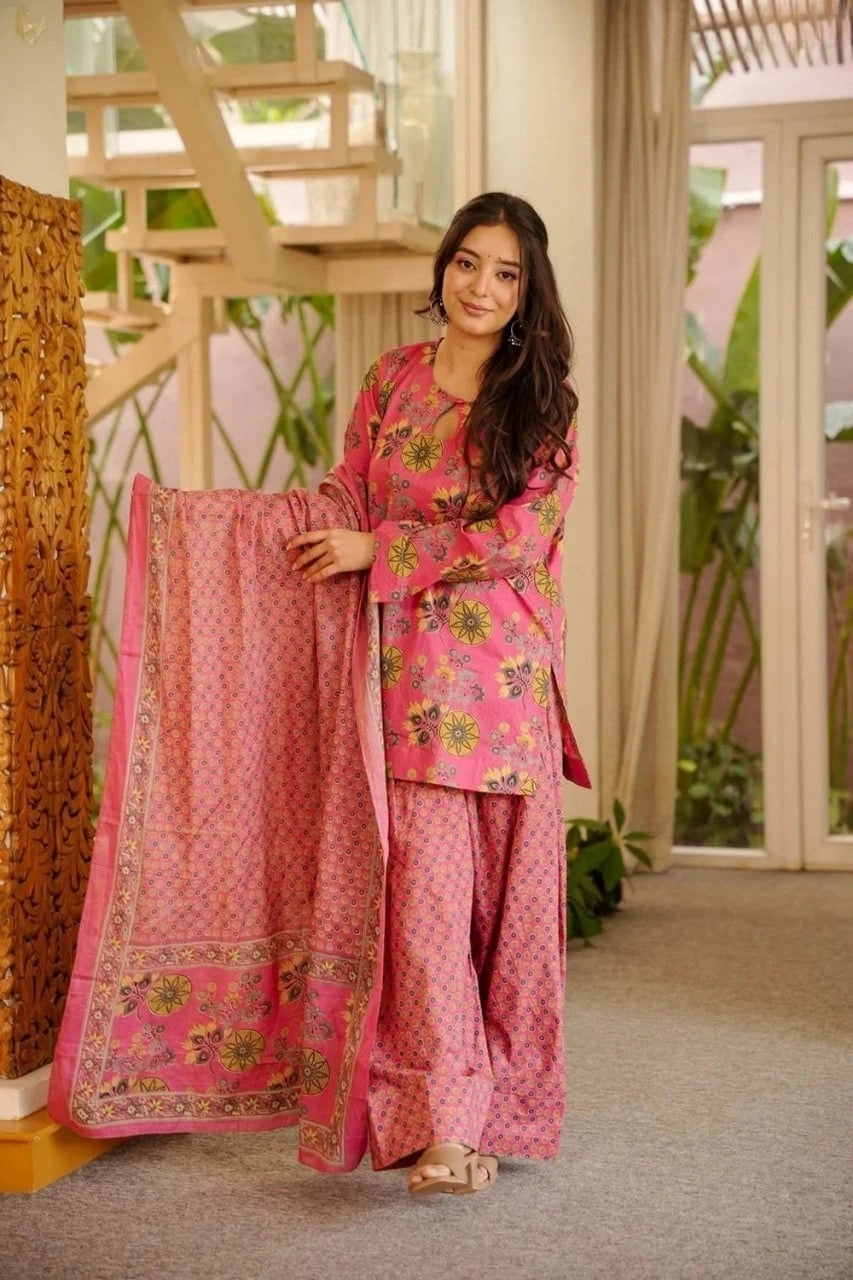 Woman in a pink traditional outfit with floral patterns indoors.