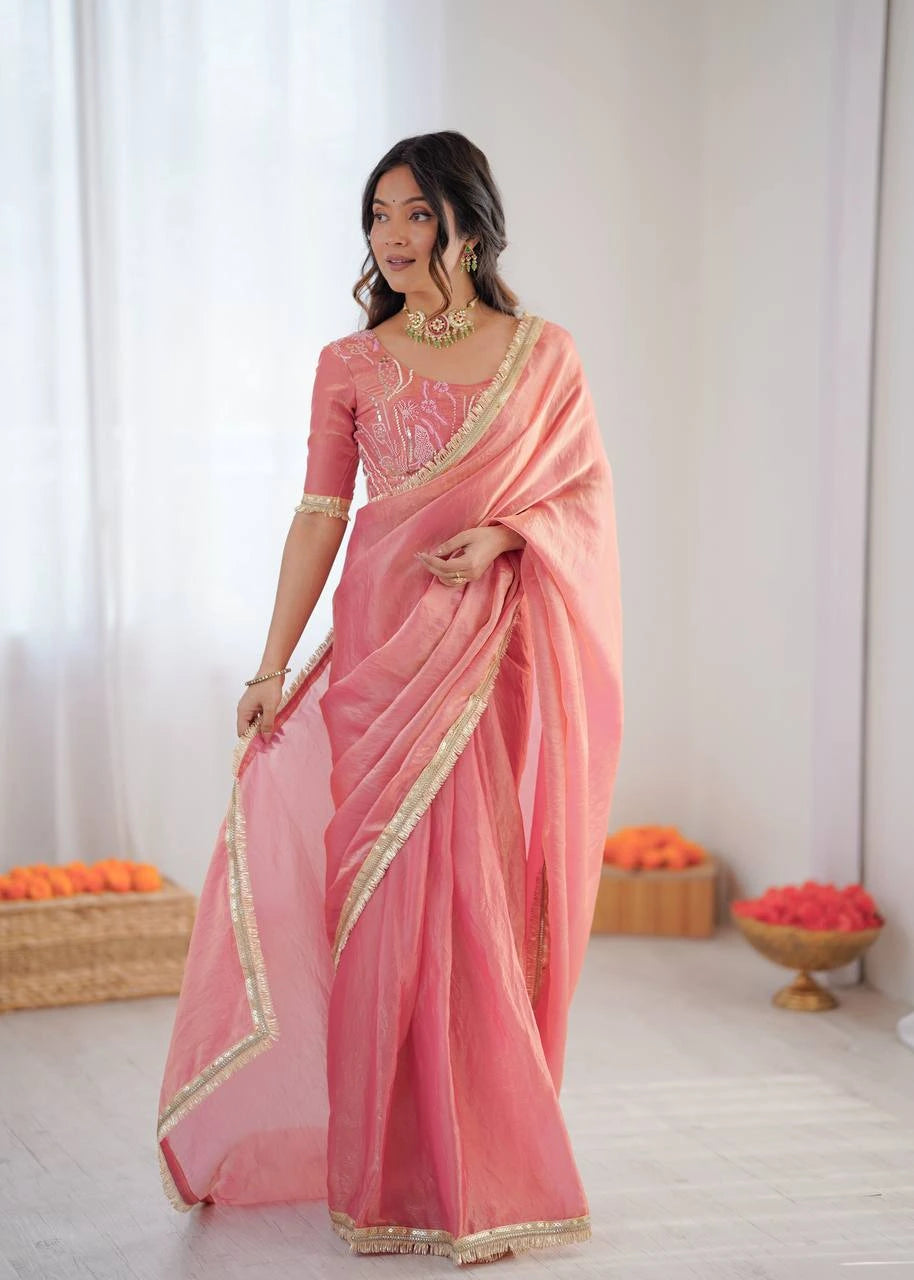 Woman wearing a pink saree with gold border indoors