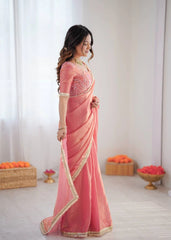 Woman wearing a pink saree with gold border indoors