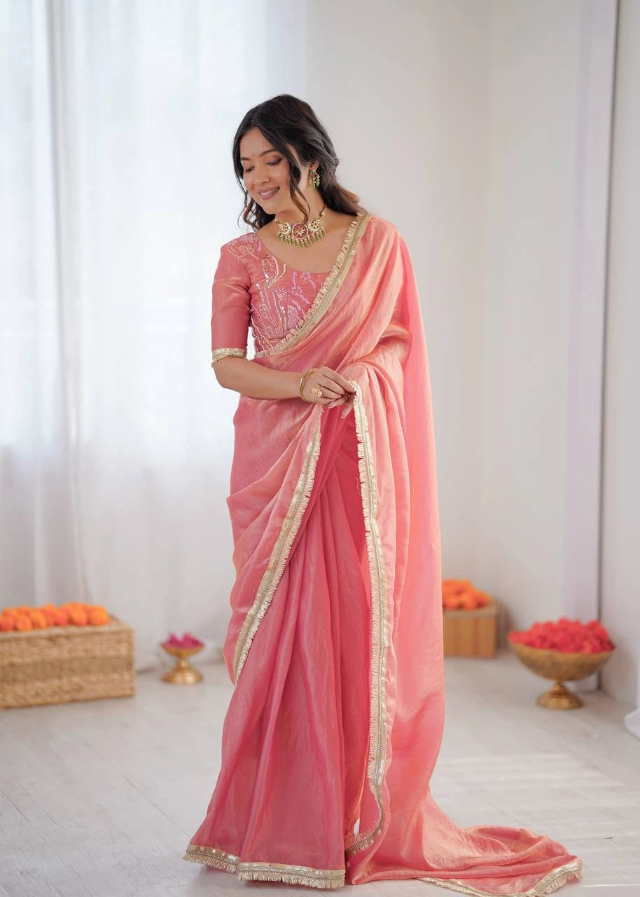 Woman wearing a pink saree with gold border indoors