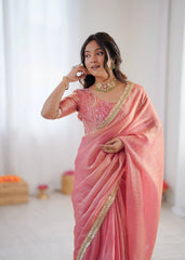 Woman wearing a pink saree with gold border indoors