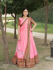 Woman wearing a pink saree with a traditional border in an outdoor setting