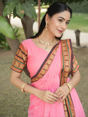 Woman wearing a pink saree with gold and green patterns outdoors.