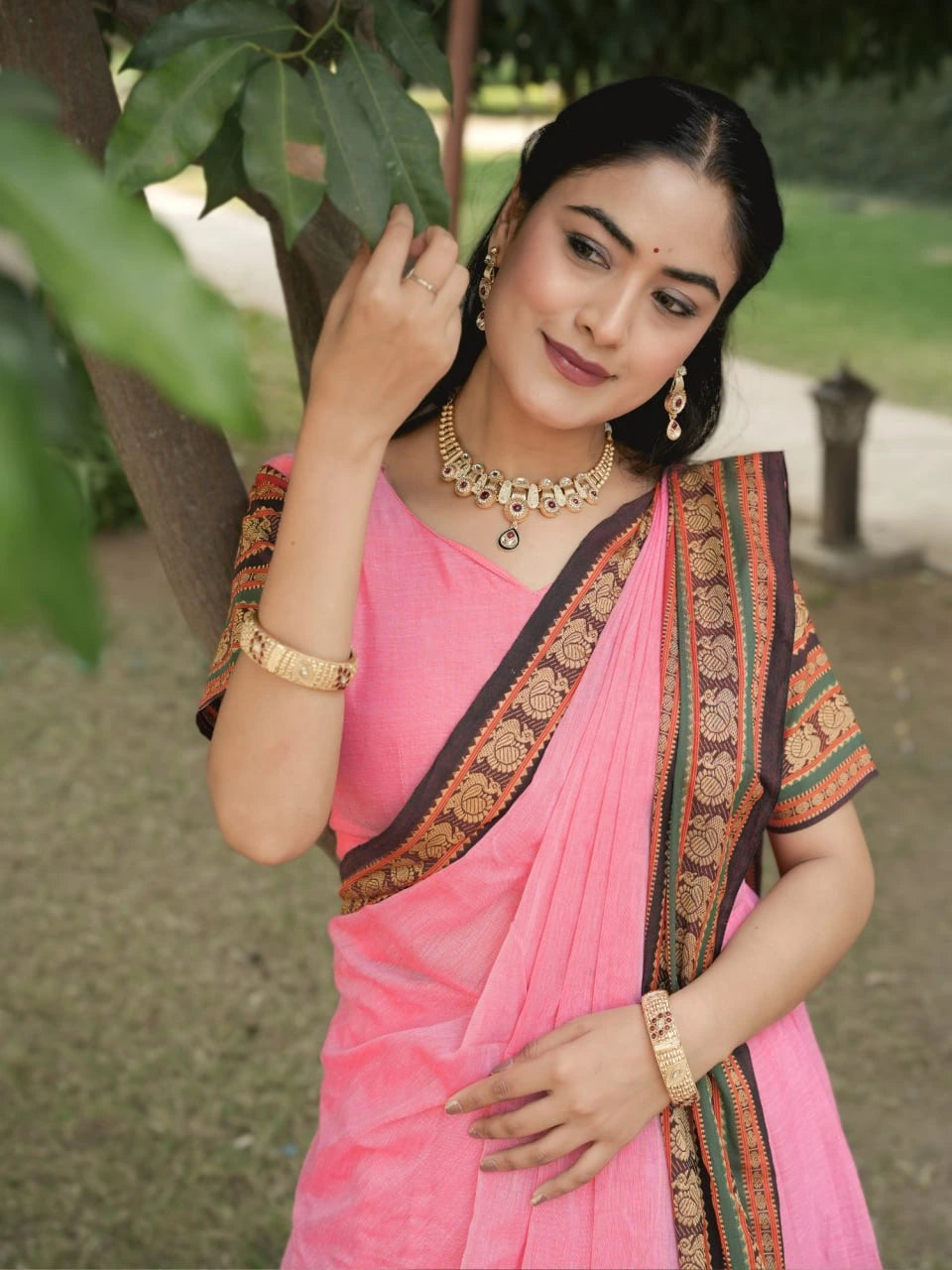 Woman in a pink saree with gold jewelry outdoors