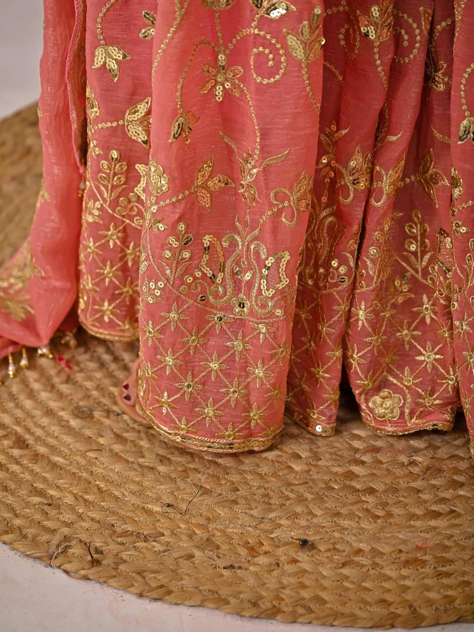 Pink fabric with gold embroidery on a textured surface