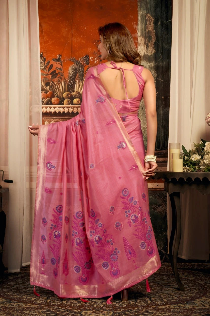 Woman wearing a pink saree with a floral pattern in an indoor setting.