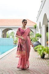 Woman in a pink saree standing by a poolside with a white building and plants in the background.