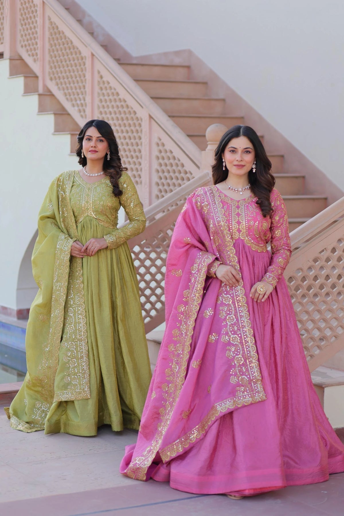 Two women in traditional embroidered dresses standing on a staircase.