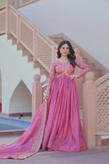 Woman in a pink traditional outfit standing in front of a staircase.