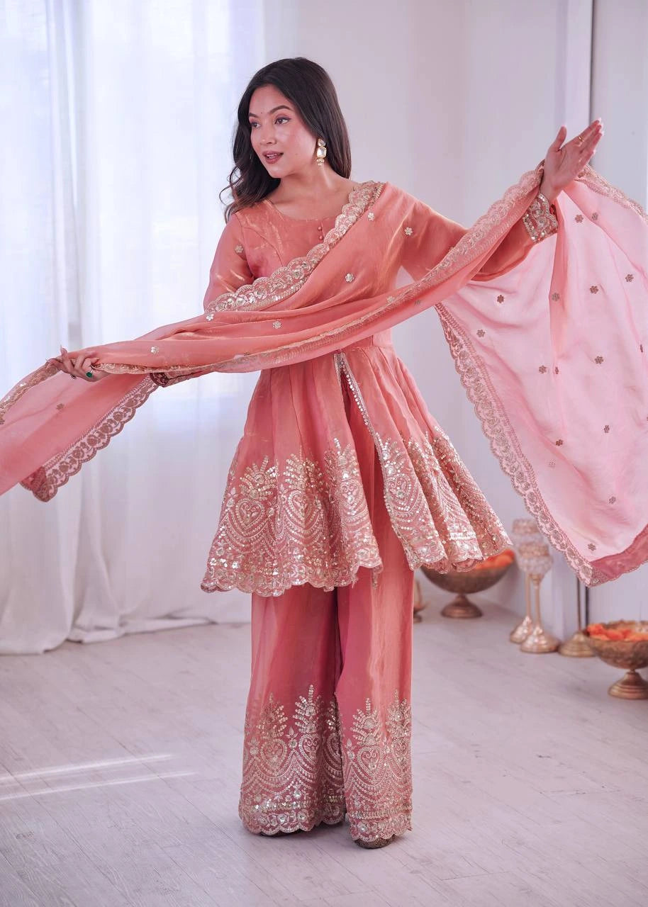 Woman in a traditional pink embroidered outfit with a white curtain background