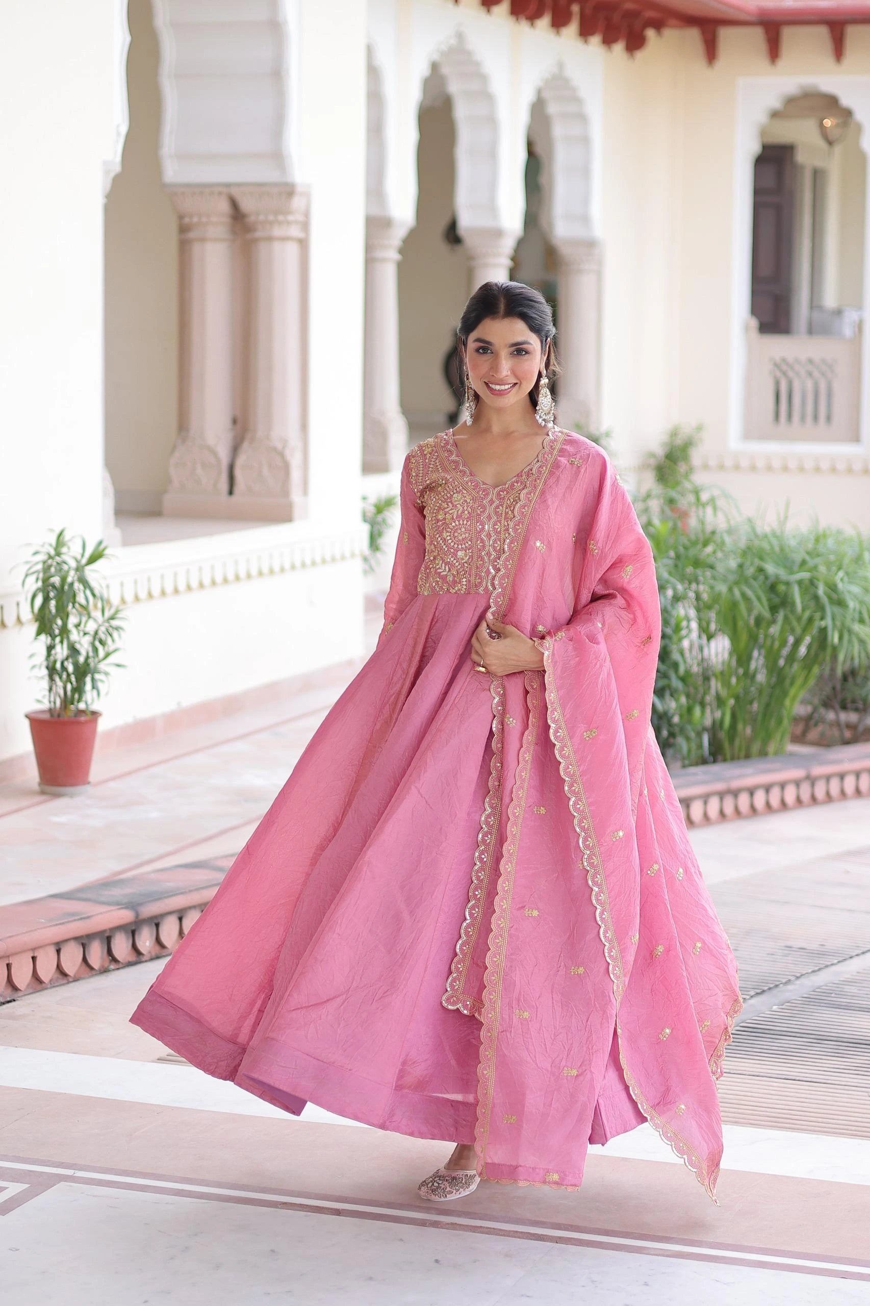 Woman in a pink traditional outfit standing in front of an architectural building.