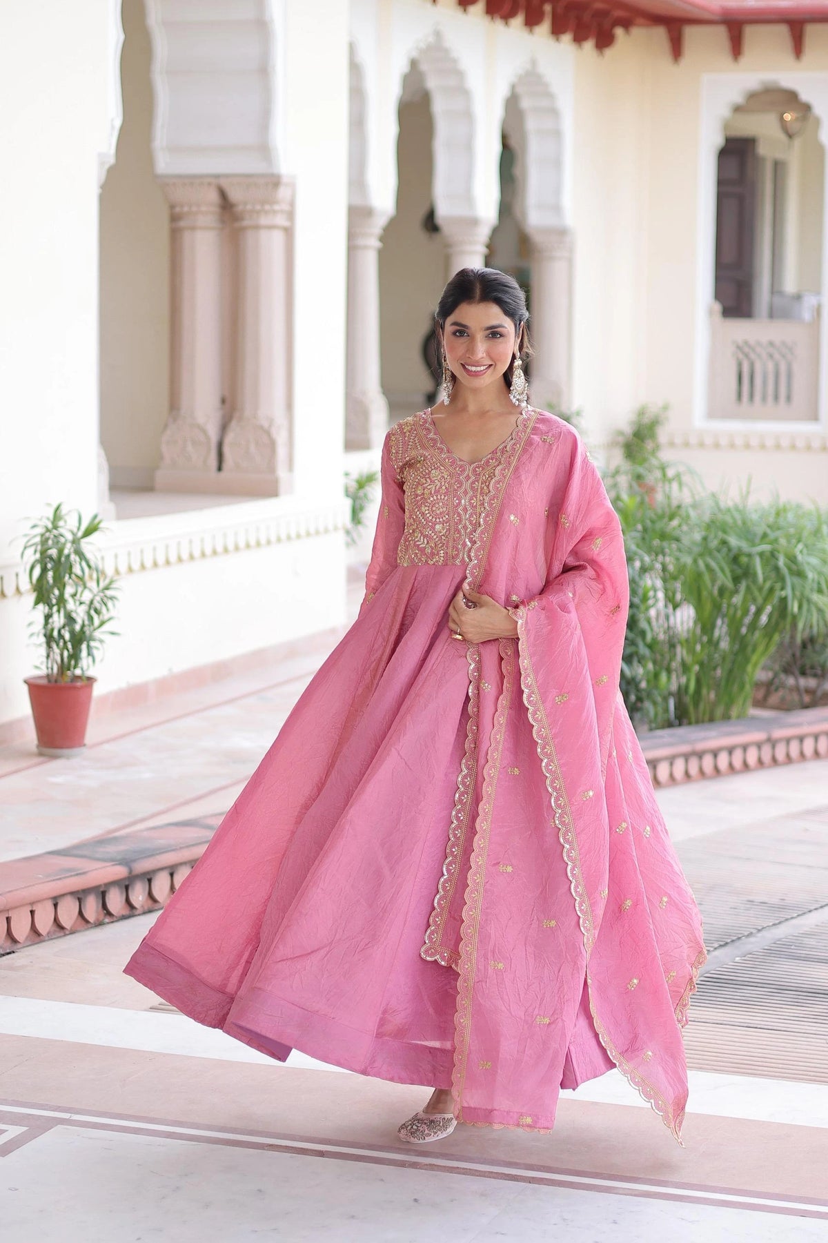 Woman in a pink traditional outfit standing in front of an architectural building.