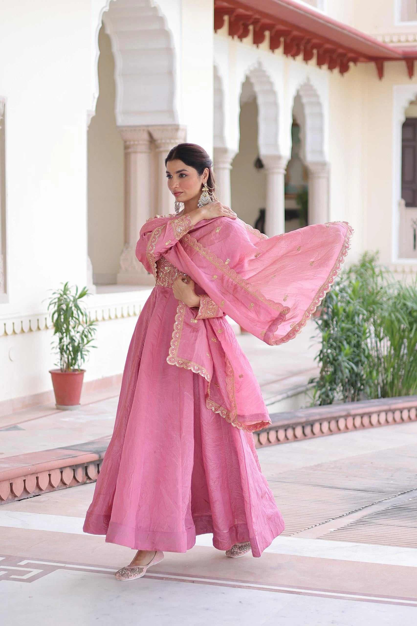 Woman in a pink traditional outfit standing in front of an architectural building.
