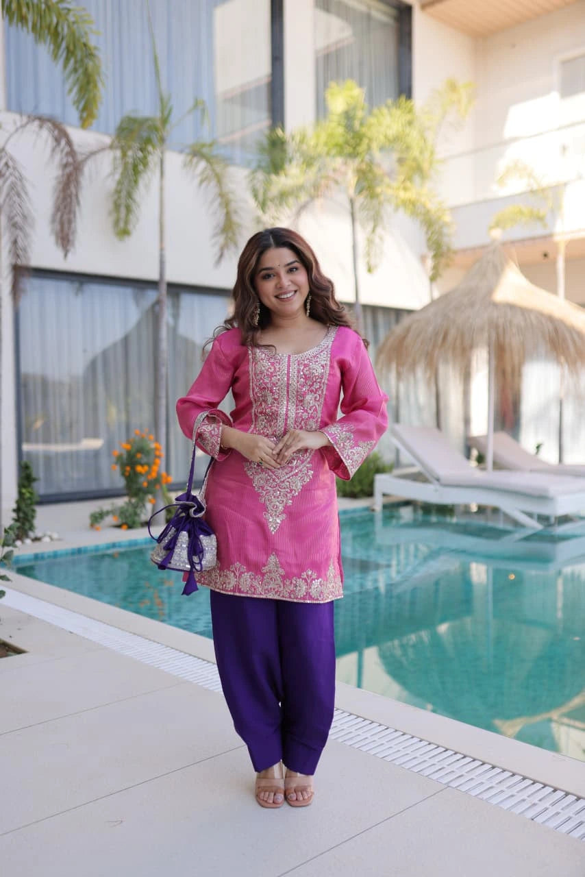 Woman in pink and purple traditional outfit standing by a pool