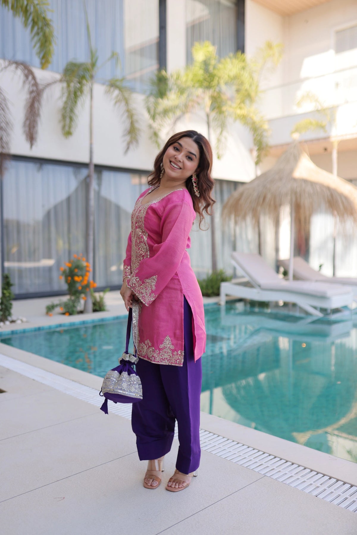 Woman in pink and purple traditional outfit standing by a poolside.