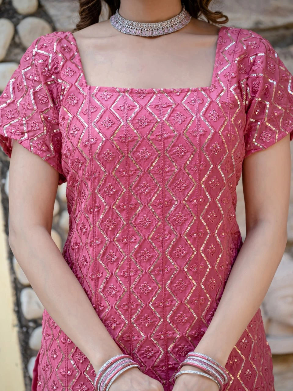 Person wearing a pink embroidered dress with a blurred background