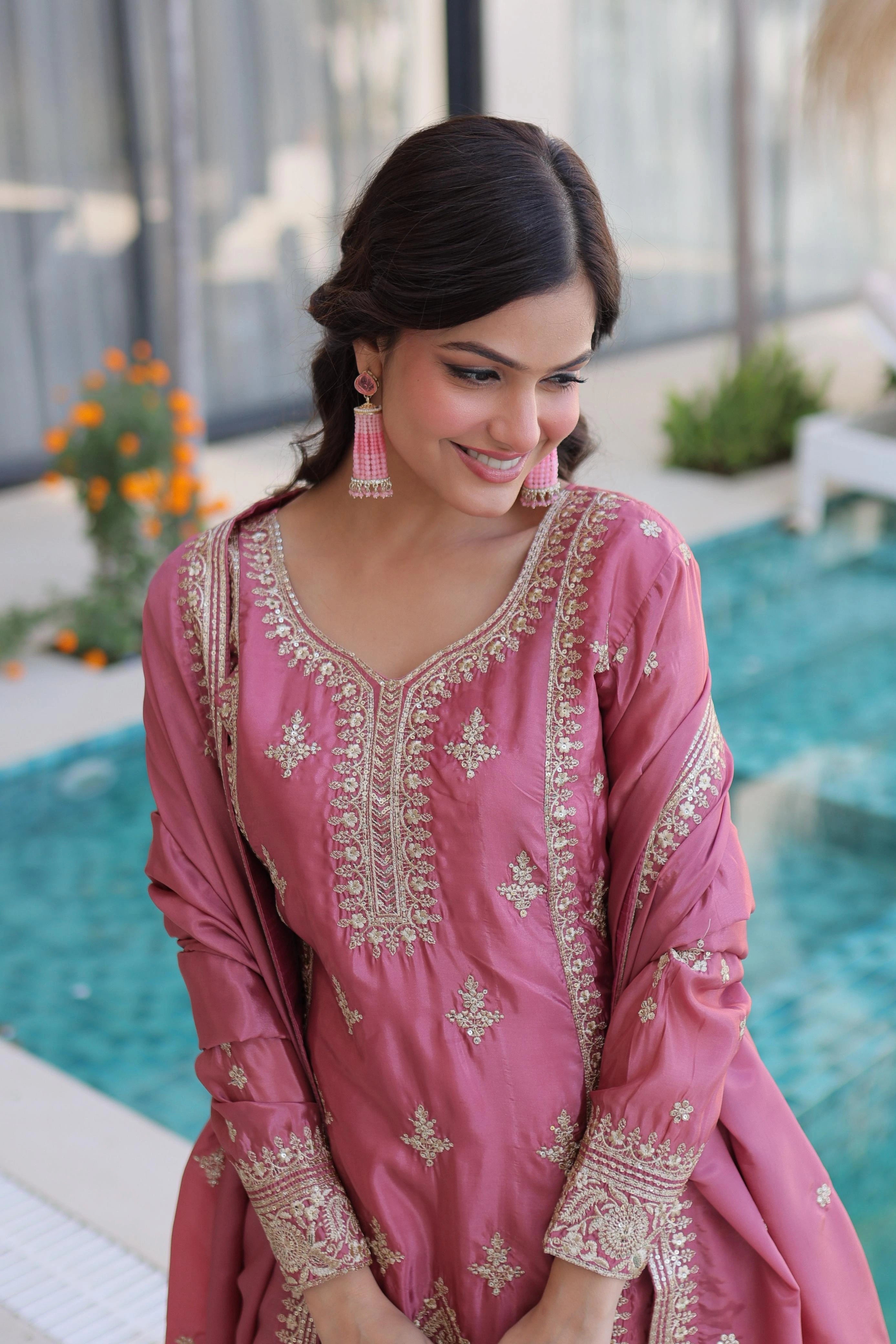 Woman in a pink embroidered traditional outfit by a poolside