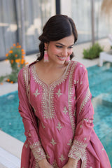 Woman in a pink embroidered traditional outfit by a poolside