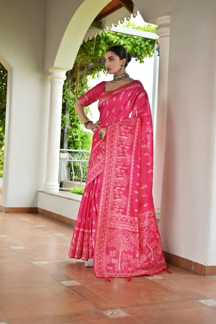 Woman wearing a pink saree with white patterns in an outdoor setting.