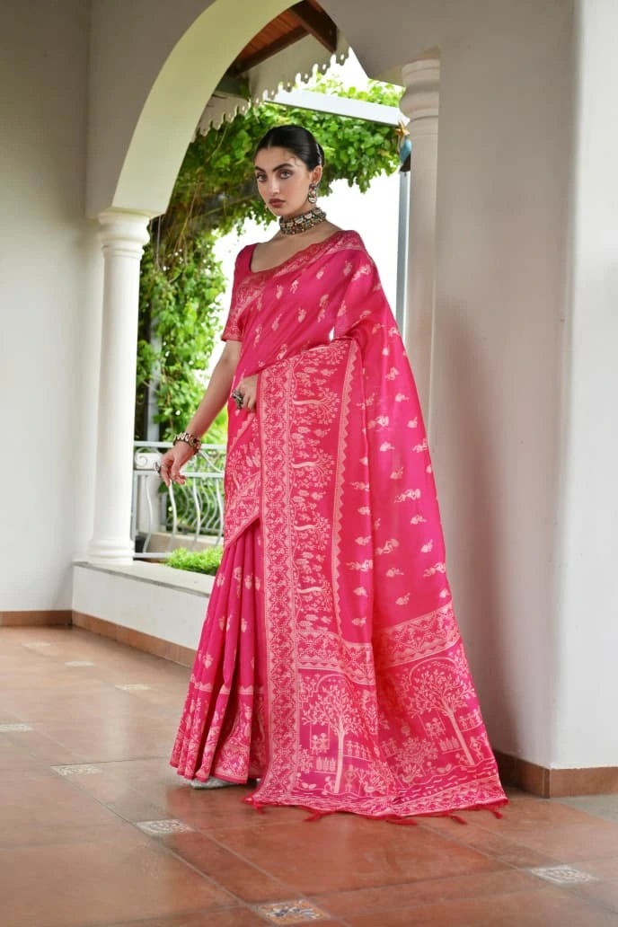 Woman wearing a bright pink saree with a white pattern indoors.