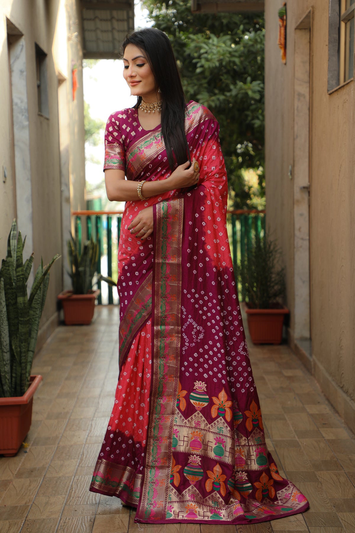 Woman wearing a traditional saree with intricate patterns in an outdoor setting.