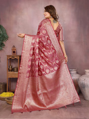 Woman wearing a pink saree with a patterned border, standing against a neutral background.