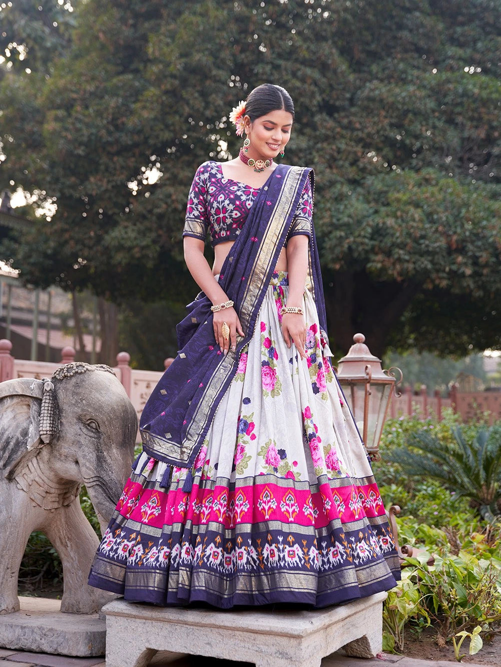 Woman in a traditional outfit with floral patterns standing outdoors.