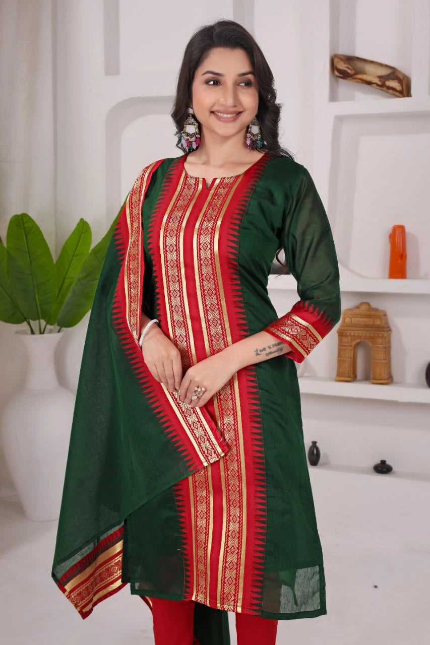 Woman wearing a green and red traditional outfit with embroidery, standing indoors.
