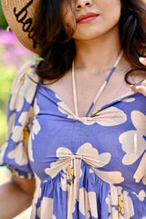 Woman wearing a blue floral dress with a straw hat outdoors