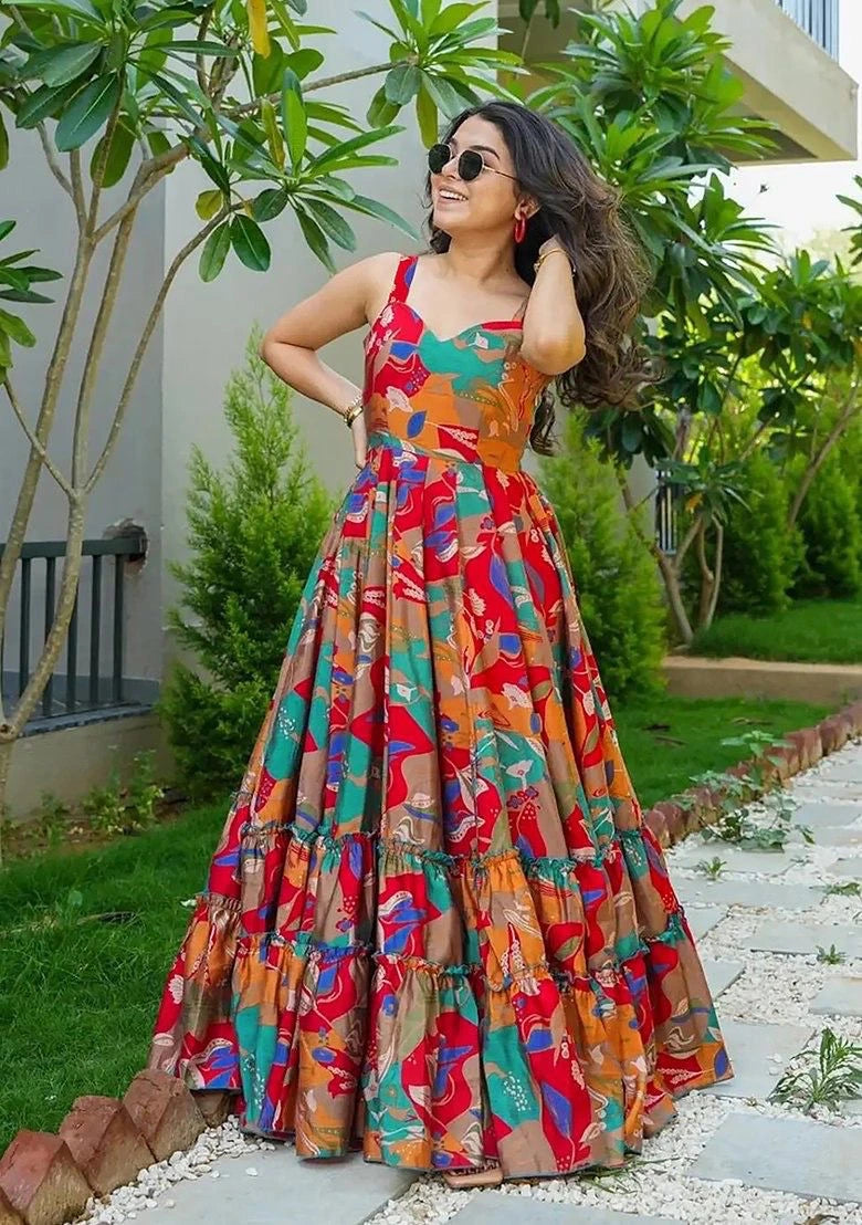 Woman in a colorful patterned dress standing outdoors with greenery in the background