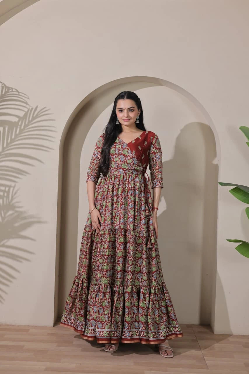 Woman wearing a patterned dress standing in front of an archway with plants on either side.