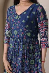 Woman wearing a blue dress with floral patterns on a plain background