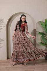Woman in a patterned dress standing in front of an archway with plants on either side.