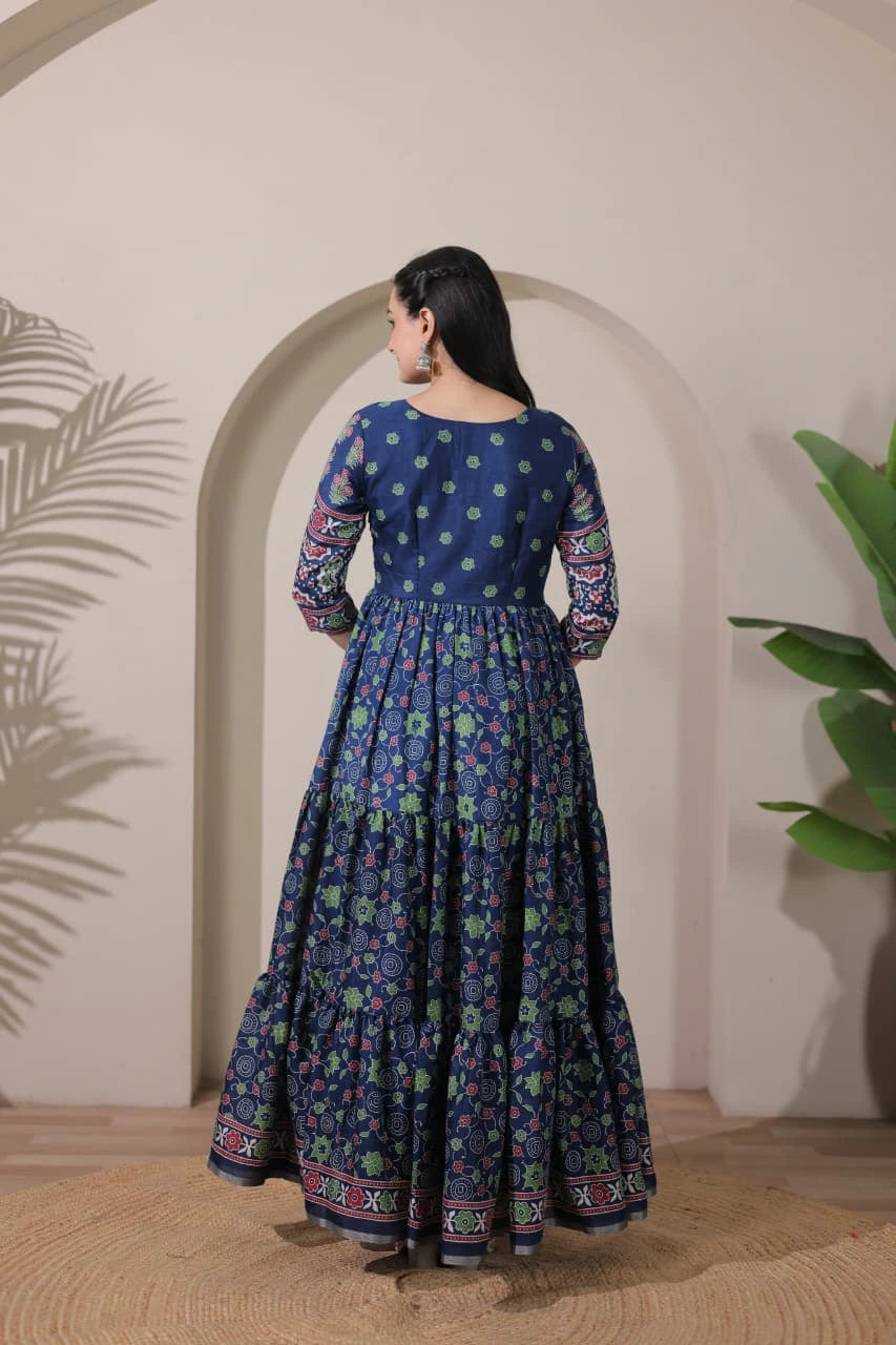 Woman wearing a blue floral dress standing in front of an archway with plants on either side.