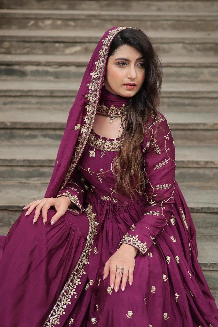 Woman in a traditional purple outfit with gold embroidery sitting on steps.