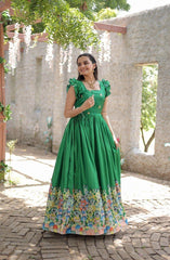 Woman in a green dress with floral pattern standing outdoors.