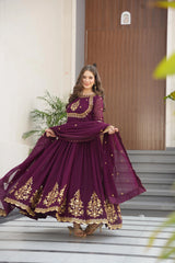 Woman in a purple traditional outfit with gold embroidery standing on a staircase.