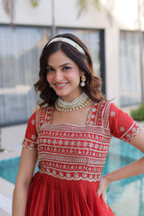 Woman in a red and white traditional outfit with jewelry, standing outdoors.
