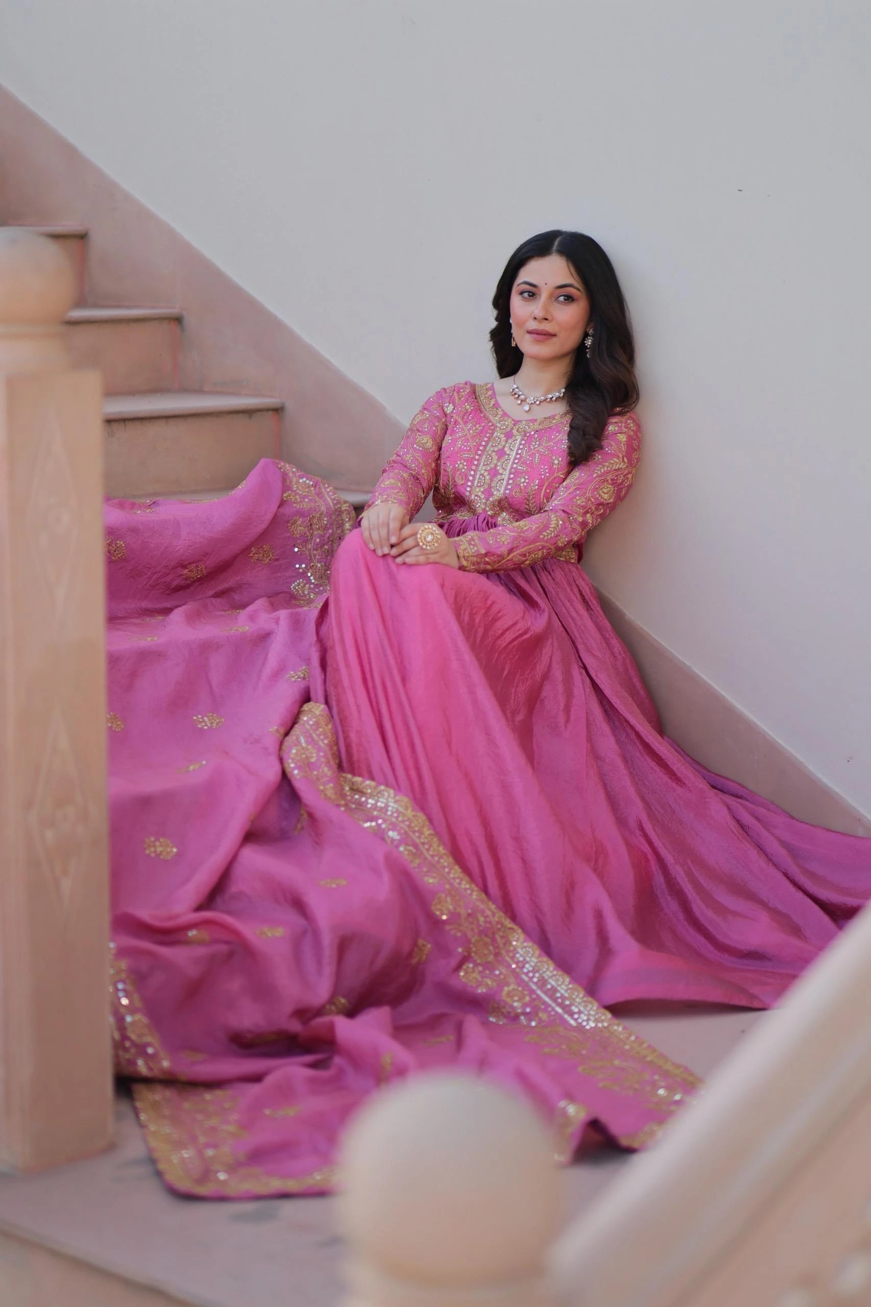 Woman in a pink traditional outfit sitting on a staircase.