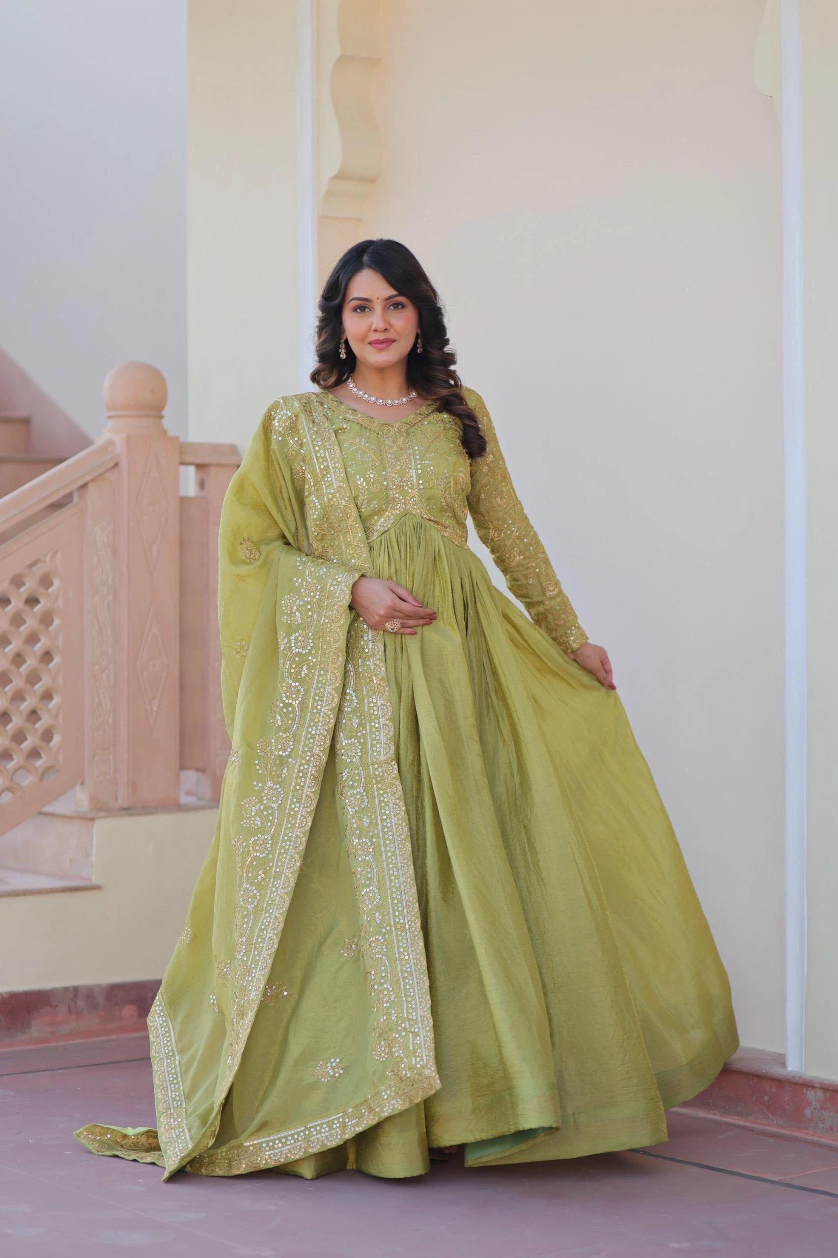 Woman wearing a green traditional outfit with embroidery in an indoor setting.