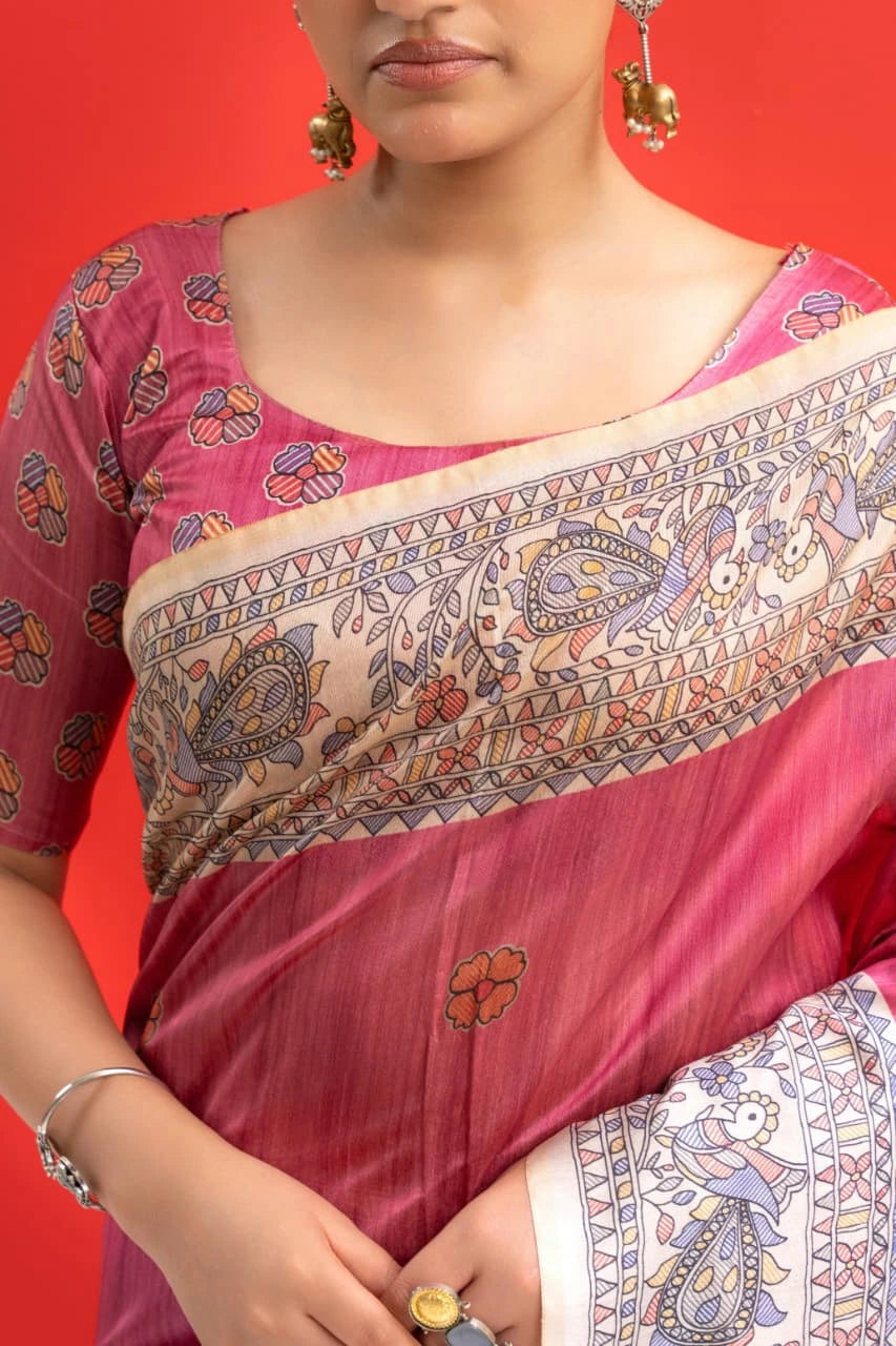 Woman wearing a pink saree with intricate patterns on a red background