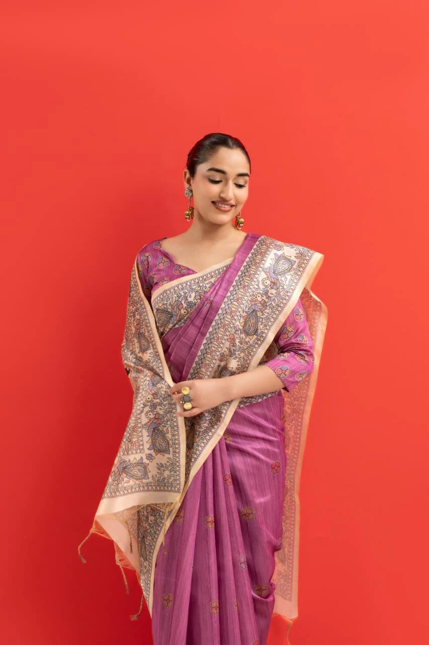 Woman wearing a pink saree with a gold border against a red background