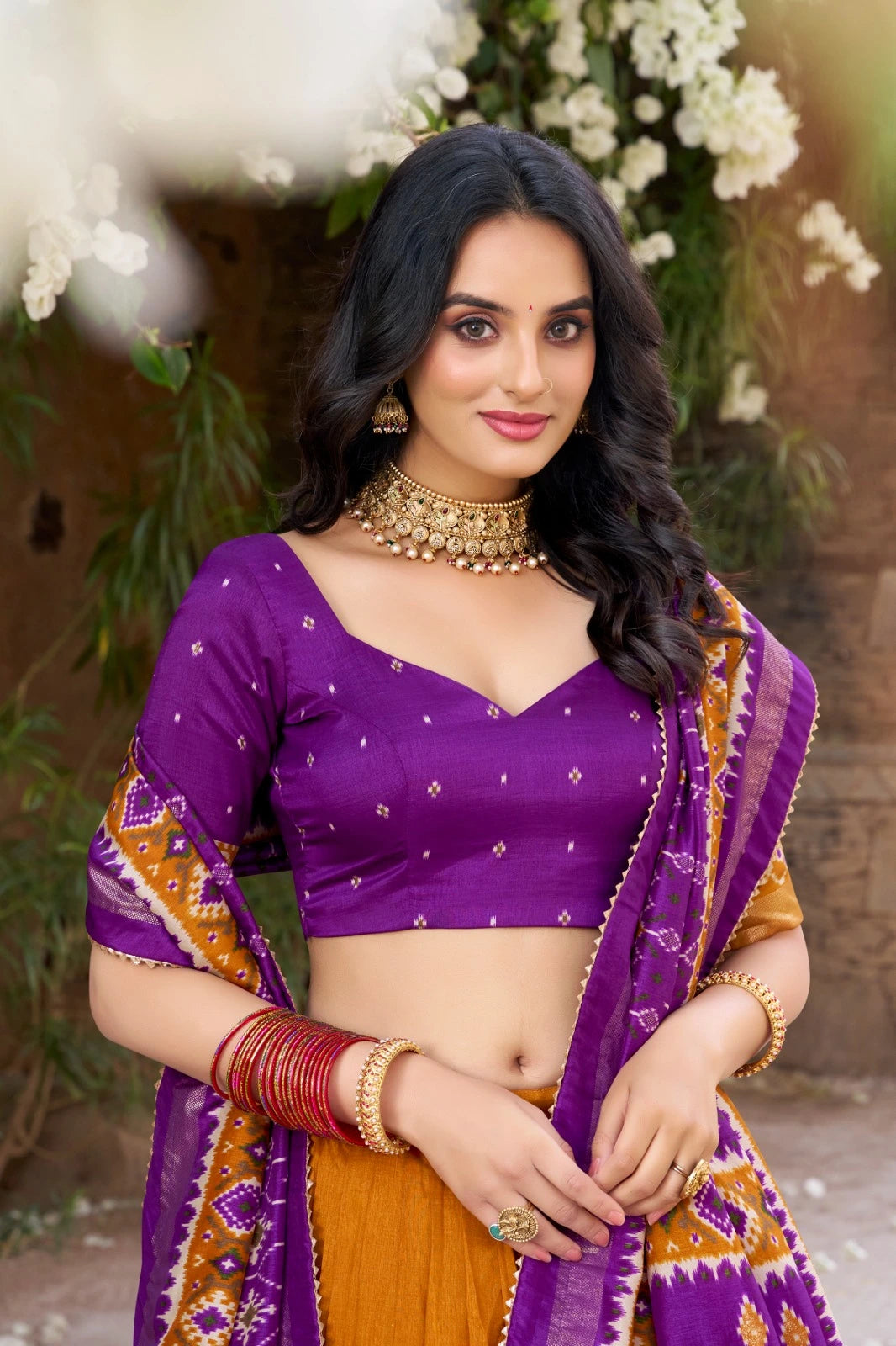 Woman in a purple and orange traditional outfit with floral background