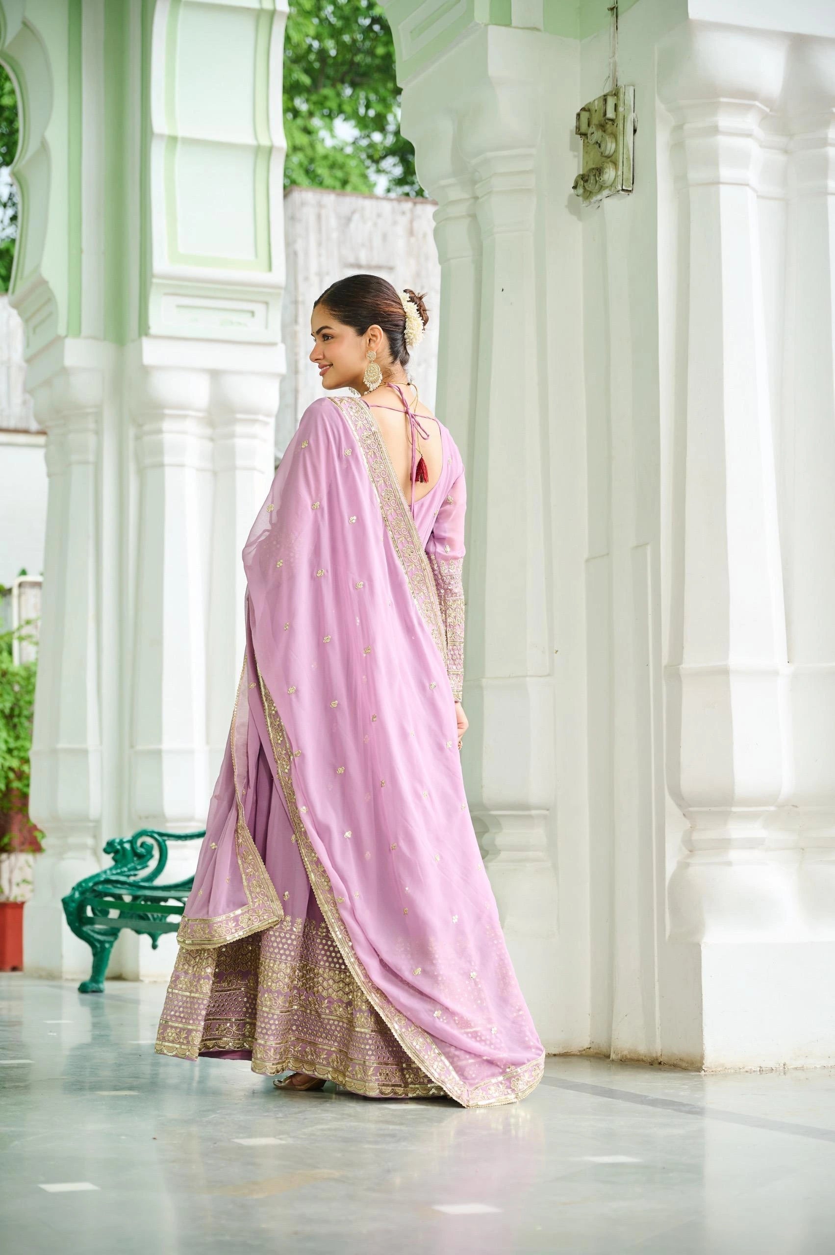 Woman in a pink saree standing in a white architectural setting