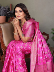 Woman in a bright pink saree sitting on a chair indoors.
