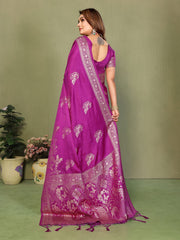 Woman wearing a purple saree with white patterns against a green background