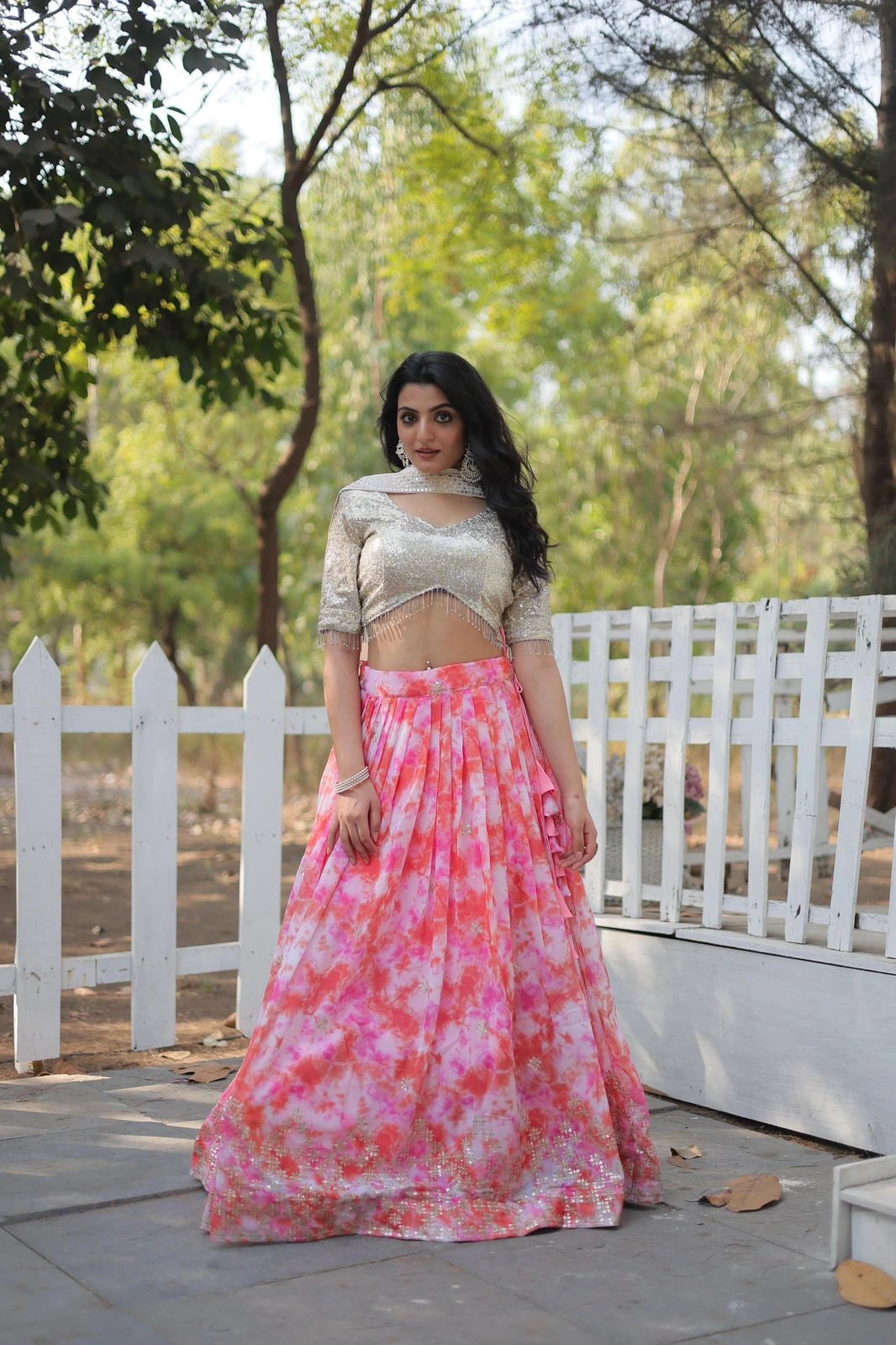 Woman in a traditional outfit with a pink and white patterned skirt standing outdoors.
