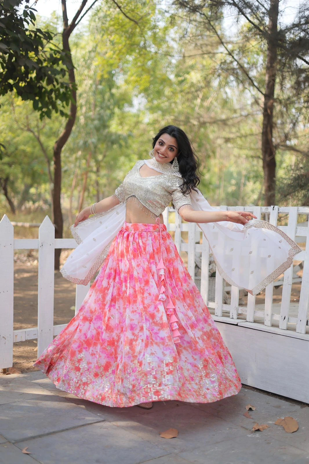Woman in a traditional outfit with a floral skirt and white top, standing outdoors.