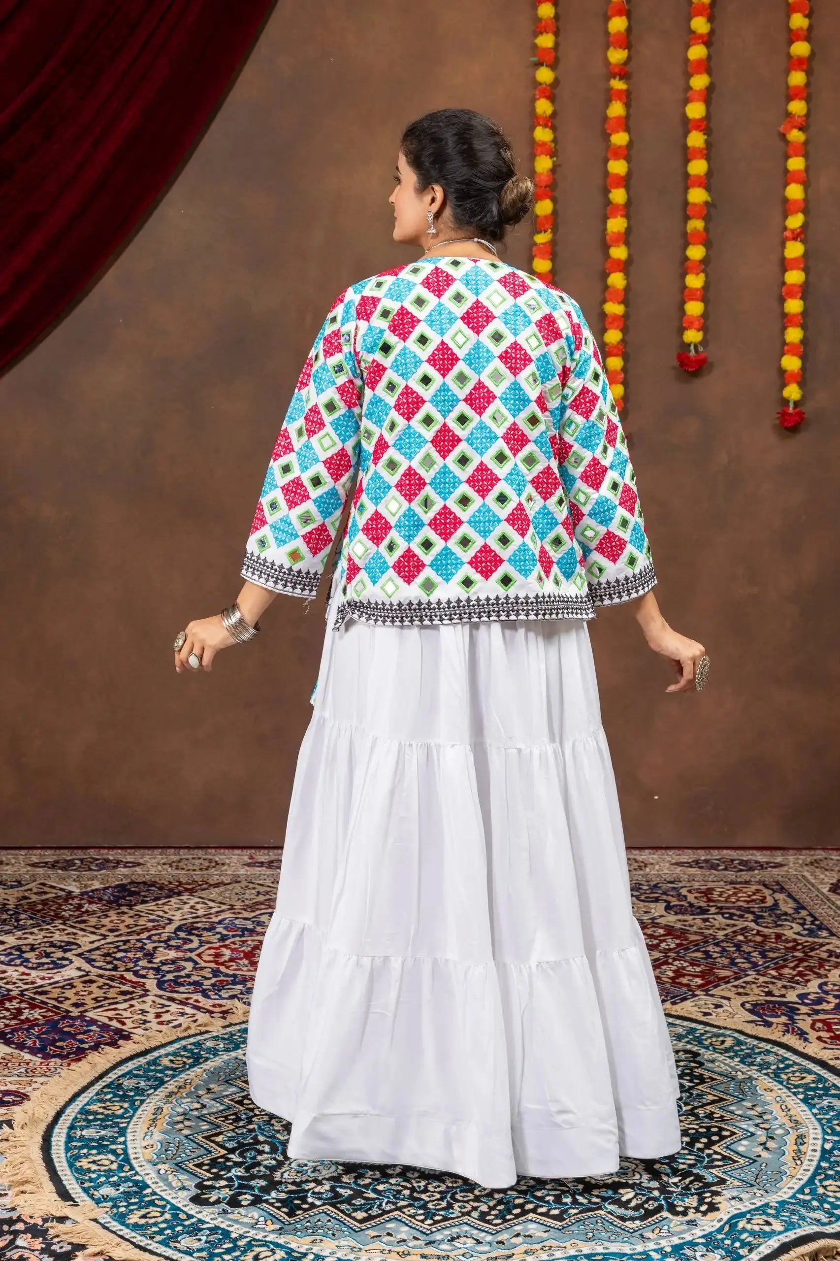Back view of white tiered lehenga showing layered skirt and back of bandhej mirror-work koti